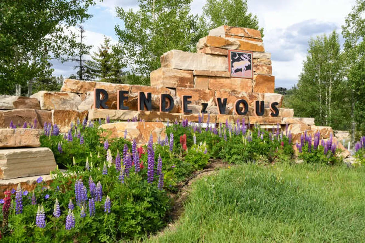 This exterior image displays the property's welcoming entrance, accented by flower beds and a stone structure. The outdoor signage and natural landscaping invite guests to explore the setting upon arrival, giving a sense of exclusive access and privacy.