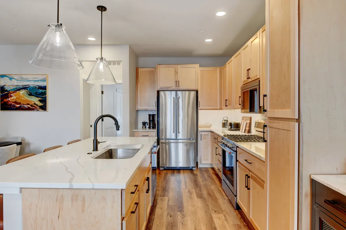 A modern, inviting kitchen featuring a large island, stainless steel appliances, and stylish lighting. The layout is ideal for preparing meals, entertaining, or gathering with friends and family throughout the year.