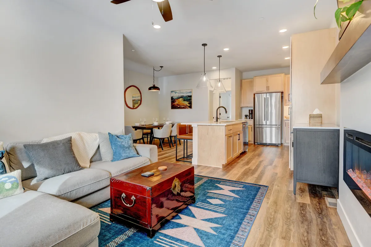 A wide, open-plan view encompassing the living area, dining space, kitchen island, and a fireplace. The arrangement encourages easy flow between relaxing, dining, and entertaining, with high-quality furnishings and an inviting atmosphere.