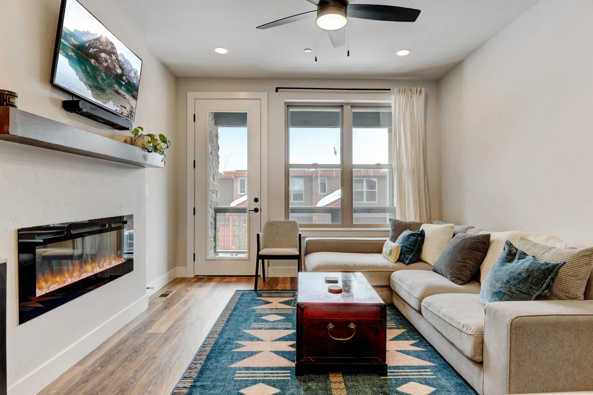 A warm and inviting living room with a couch, cozy rug, fireplace, and television. The space is made for relaxing evenings, socializing, or enjoying movie nights after a day spent exploring seasonal activities.