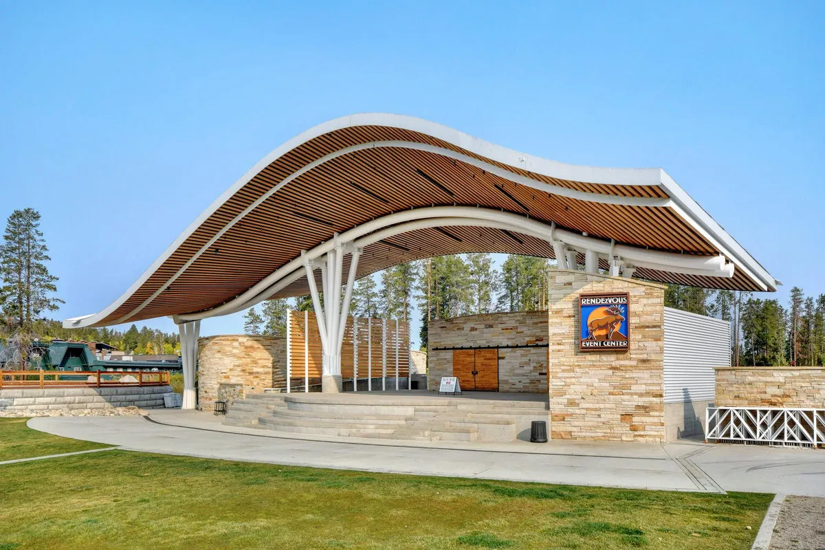 The distinctive wave-like stone façade and clear signage of the event center with open space for gatherings. The setting hints at outdoor concerts and vibrant community events, echoing the mention of Hideaway Park amphitheater and local happenings.