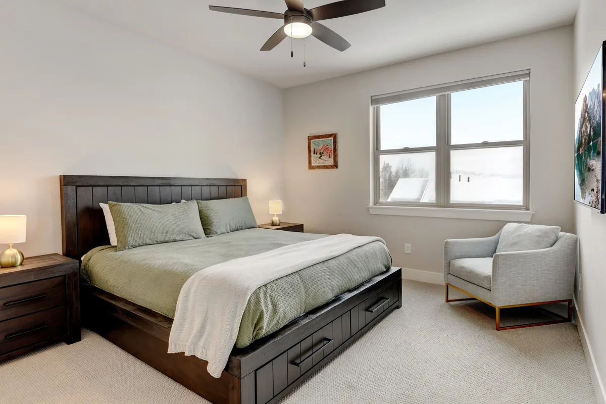 A serene bedroom with a comfortable bed, armchair, nightstand, and large window allowing in natural light. The space is perfect for restful mornings, reading, or unwinding after a day out in Winter Park.