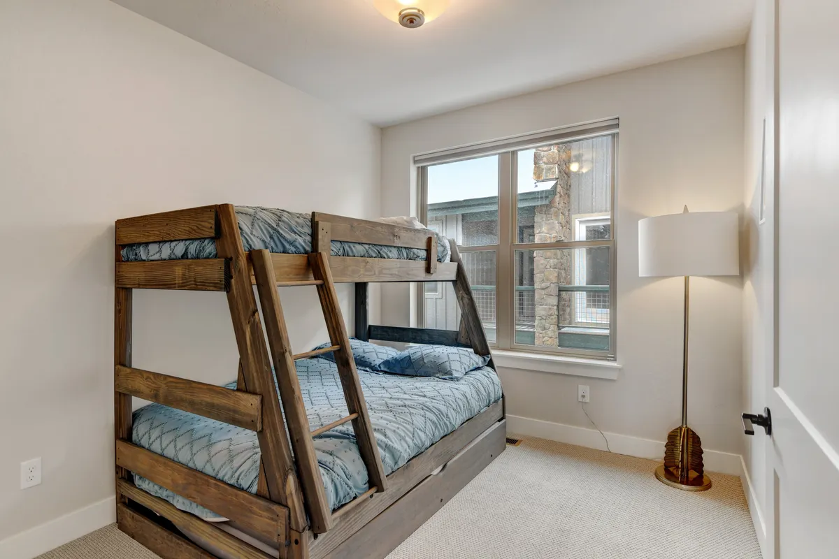 A cozy, kid-friendly bunk bed area illuminated by natural light from a nearby window. The setting is designed for children’s comfort, play, and sleep, fostering a sense of adventure and togetherness.