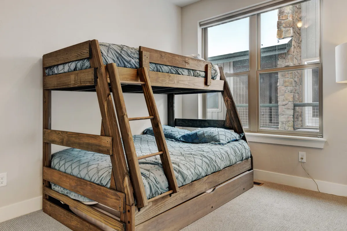 A cozy bunk room with sturdy bunk beds, crisp bed linens, and a sunlit window. This inviting space is designed for children, perfect for sleepovers or families traveling with kids.