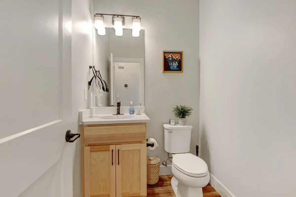 A bright bathroom featuring a stylish vanity with sink, an elegant mirror, calming artwork, and a touch of greenery. The overall look is inviting and serene, with thoughtful amenities for self-care routines.